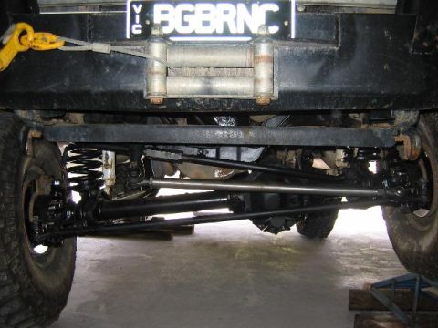 1982 Ford Bronco - Front underside view of a dark-colored Ford Bronco showing the front axle, coil springs, radius arms and track bar suspension, with a winch…