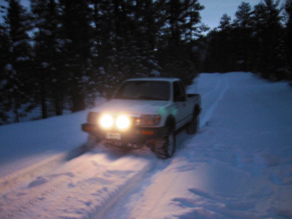 1999 Toyota Tacoma driving through snow with headlights on