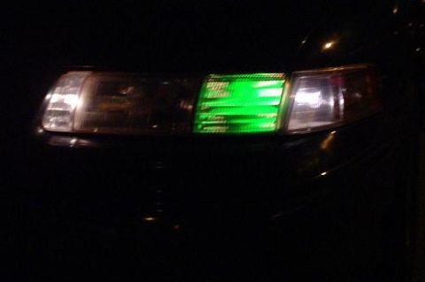 1993 Ford Taurus - A car's headlight features a custom green digital display, showing text in the dark.