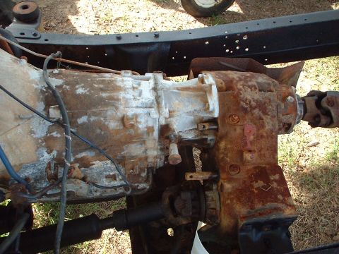 1976 Ford F-150 - Close-up view of a heavily rusted transmission and driveshaft assembly, likely from an older truck.