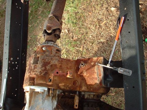 1976 Ford F-150 - A heavily rusted transfer case and driveshaft assembly are shown, with tools present.