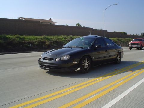 1993 Ford Taurus - A black sedan with aftermarket wheels is seen on the highway.