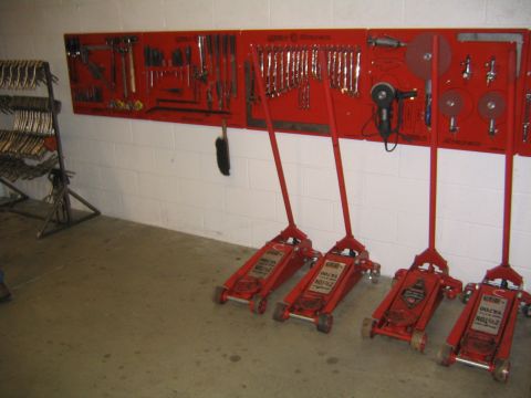 1978 Ford Bronco - A collection of tools and equipment, including four red floor jacks and a wall-mounted tool board, are displayed in a workshop setting.