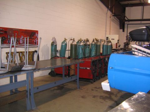 1978 Ford Bronco - A blue vehicle door is visible next to welding equipment and gas cylinders in a workshop setting.