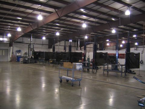 1978 Ford Bronco - The wide shot shows a large workshop space equipped with car lifts and welding stations, ready for automotive work.