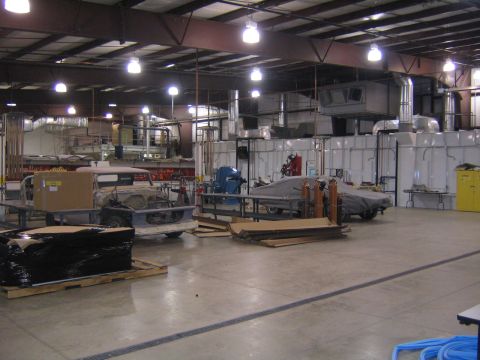 1978 Ford Bronco - Workshop scene with a vehicle chassis in the foreground and a covered vehicle in the background.