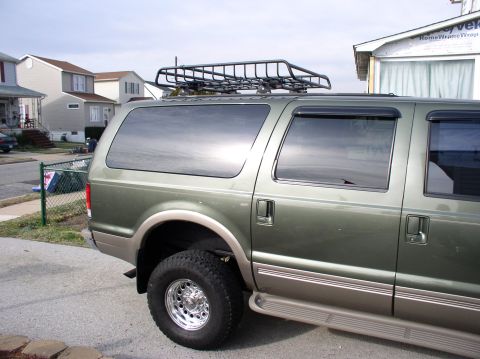 2000 Ford Excursion - The side profile of a green Ford Excursion SUV equipped with a roof rack and running boards.