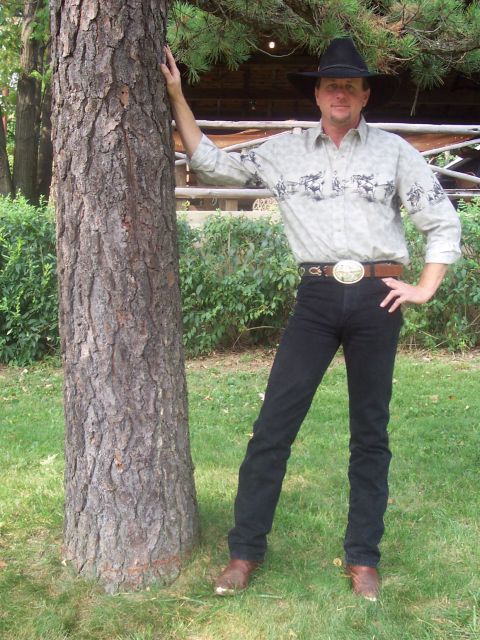 1994 Ford Bronco - A man dressed in western wear poses next to a large tree in a grassy outdoor setting.