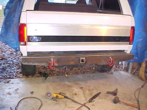 1994 Ford Bronco - The rear of a 1994 Ford Bronco shows a custom bumper with red tow hooks and the Ford emblem.