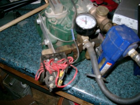 1996 Ford Bronco - Close-up of an air compressor unit, showing its pressure gauge, wiring, and blue nozzle.