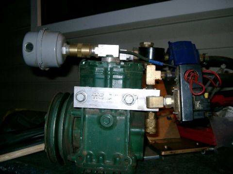 1996 Ford Bronco - Close-up of an air conditioning compressor with various fittings and a blue solenoid valve.
