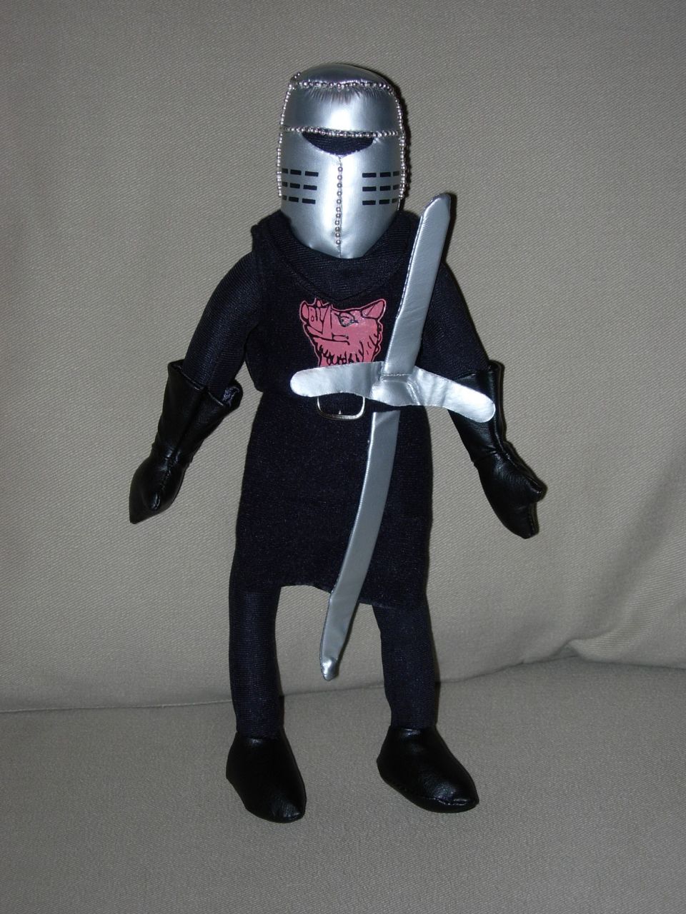 Plush toy knight wearing silver helmet and black outfit, holding a silver sword