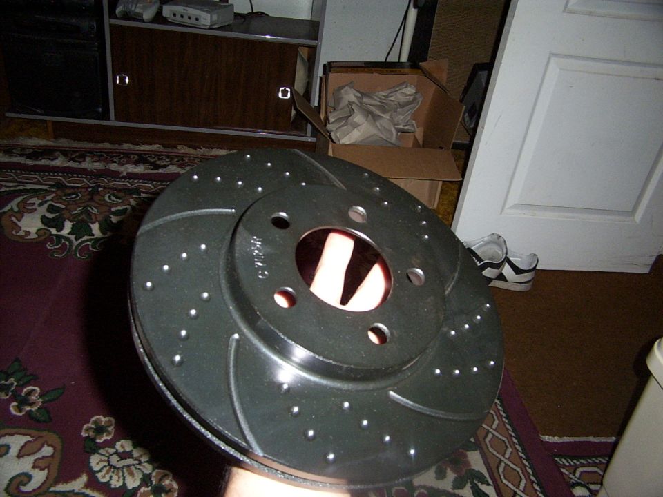 drilled and slotted brake rotor held in hand