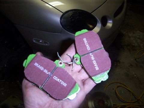 1998 Mercury Sable - New brake pads ready for installation, showing the 'BRAKE-IN COATING' label.