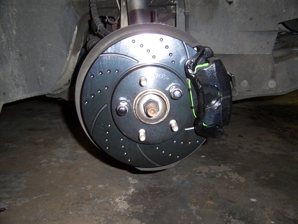 Drilled and slotted brake rotor with black caliper and green accents