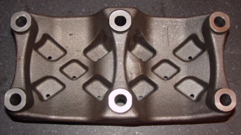 1969 Ford Fairlane - A dark gray, cast iron engine bracket with a symmetrical design diamond-shaped recesses and circular bolt holes.