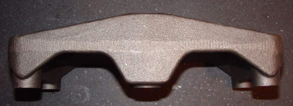 Bare cast-iron rocker shaft stand saddle on a dark surface