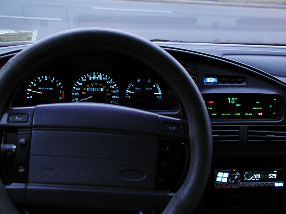 Dashboard of a 1992 Ford Taurus showing illuminated gauges, steering wheel, and radio