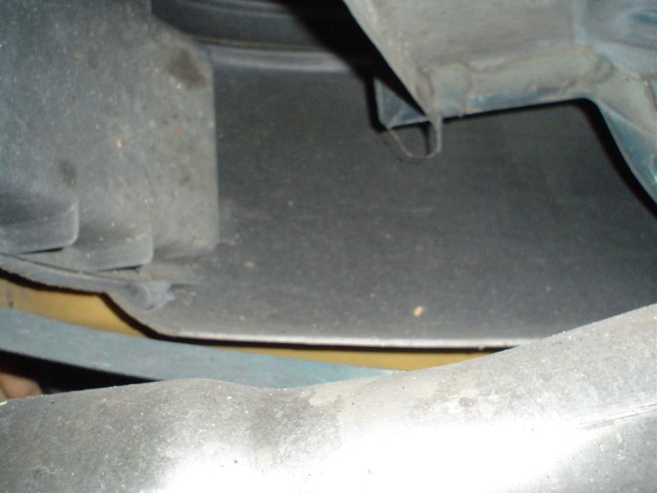 Close-up of a car's wheel well liner, showing plastic and metal components