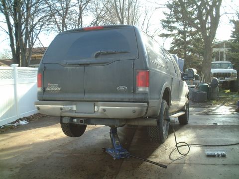 2000 Ford Excursion - A Ford Excursion is being worked on in a driveway, with a second vehicle visible in the background.