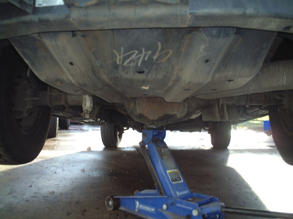 Underside of vehicle on blue Michelin floor jack in a garage
