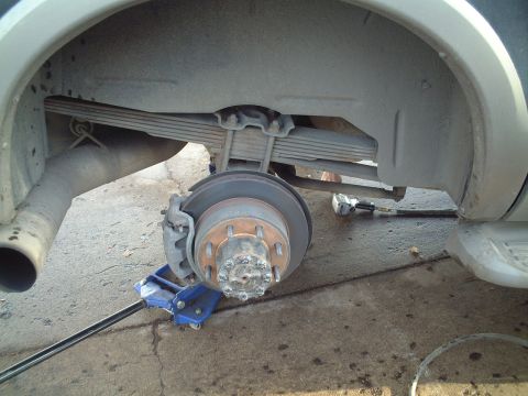 2000 Ford Excursion - The rear axle and suspension components of a vehicle are shown with the wheel removed.