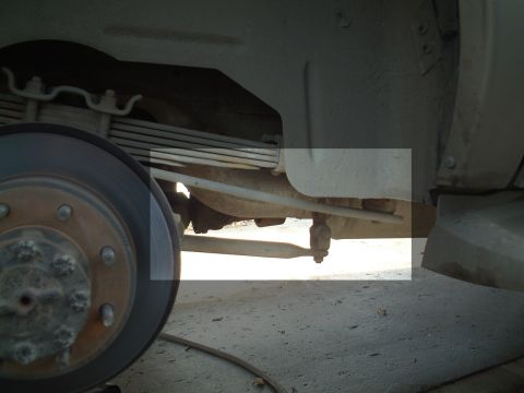 2000 Ford Excursion - A close-up view of a vehicle's undercarriage focuses on the suspension components and brake system.