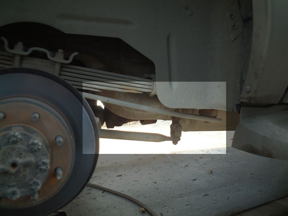 Underside of vehicle showing leaf spring, brake rotor, hub and suspension linkage