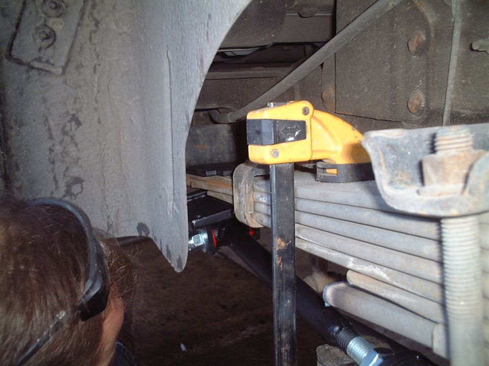 Leaf spring suspension underside with yellow clamp tool and rusty U-bolts