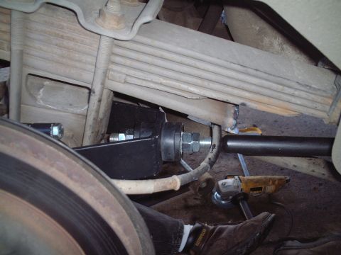 2000 Ford Excursion - Mechanic working on the rear suspension of a vehicle, installing a new component with bolts and nuts.