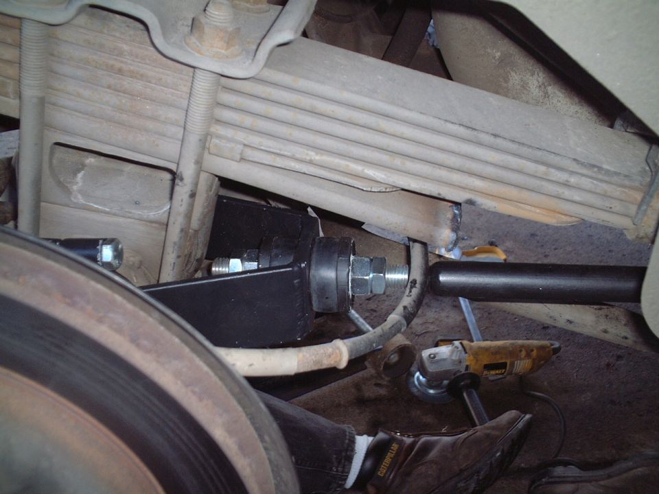 Underside leaf-spring suspension with bolt, black bracket, DeWalt grinder and work boot