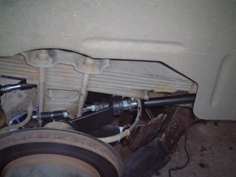 2000 Ford Excursion - Close-up view of vehicle suspension components and a person's legs during installation.