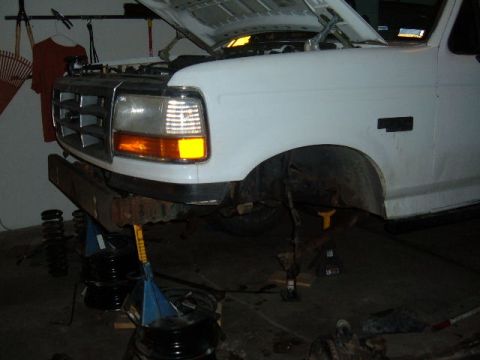 1993 Ford Bronco - Front view of a white truck with its hood open, supported by jack stands for maintenance. The body style suggests a 1992 model year.