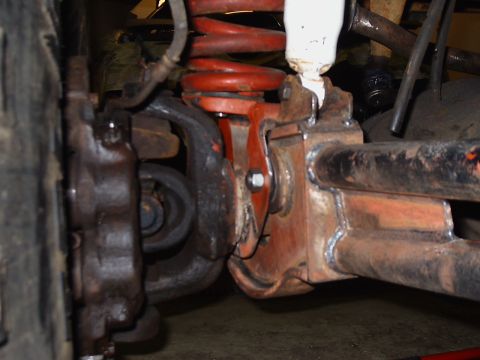 1996 Ford Bronco - Detail of a vehicle's front suspension system, showing the brake caliper, coil spring, and suspension components.