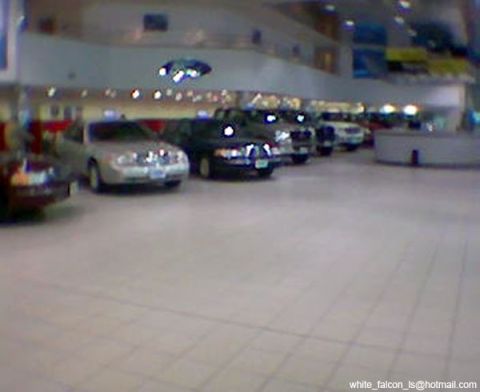 1999 Mercury Grand Marquis - A silver 1999 Mercury Grand Marquis is parked in a showroom alongside other vehicles.