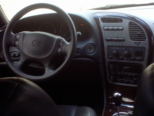 Oldsmobile interior, leather-wrapped steering wheel with Olds emblem, wood-trim center stack and shifter