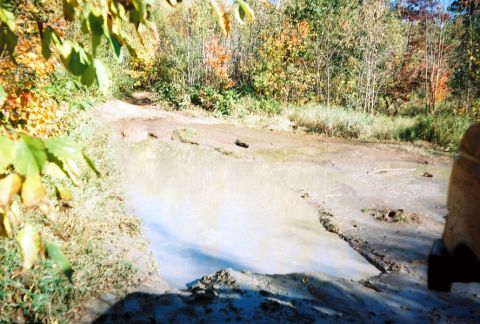 1989 Ford Bronco - A vehicle navigates a muddy trail during autumn.