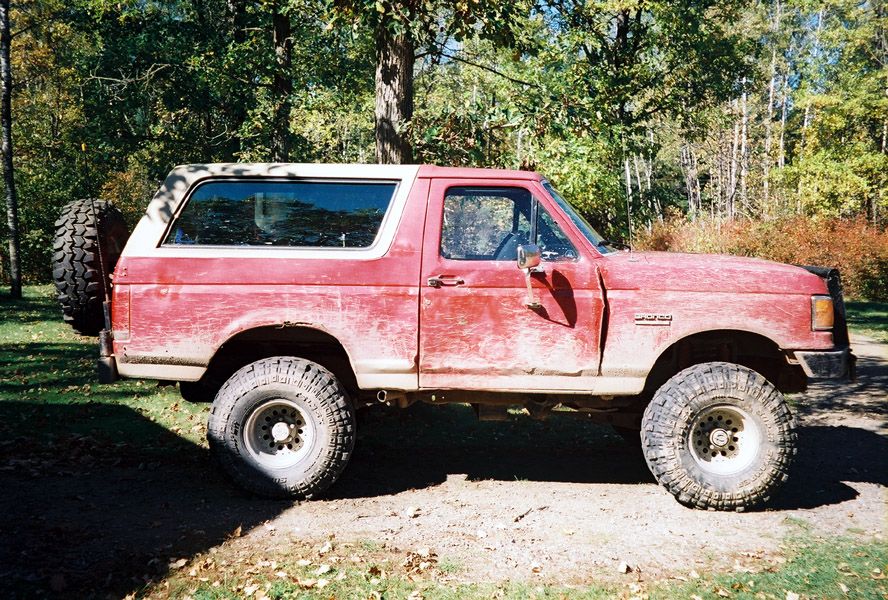 Red 1989 Ford Bronco side view with spare tire on rear door