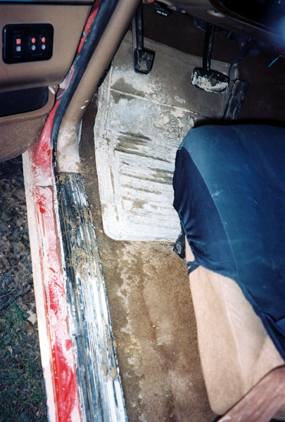 1989 Ford Bronco - The interior of a vehicle shows a dirty floor, pedals, and part of a seat, with no visible year identification.