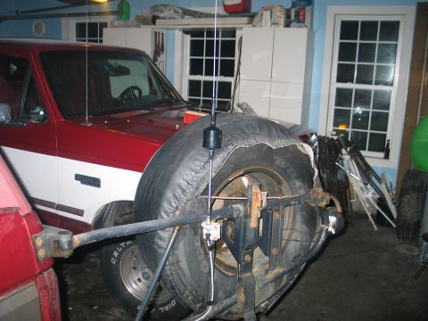 1995 Ford Bronco - A red and white Ford Bronco is parked in a garage, with a spare tire visible on the rear.