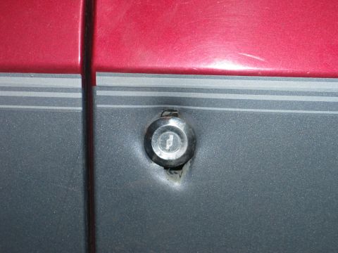 1995 Ford Bronco - Close-up of the door lock cylinder on a 1995 Ford Bronco, showing the vehicle's two-tone paint scheme.