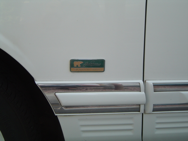 Jack Nicklaus Signature Series badge on white Lincoln Town Car fender above chrome body molding