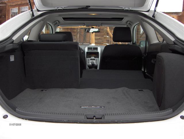 Black interior rear cargo view of a hatchback through open rear hatch with gray carpet floor