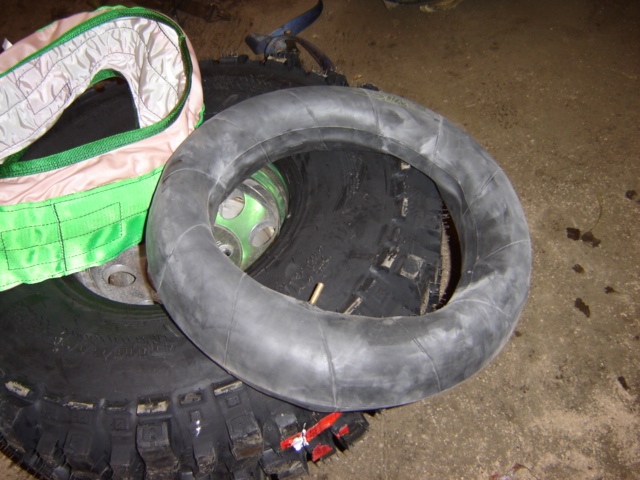 Tire inner tube lying on top of a large tire. A green and white strap is visible to the left