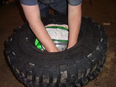 1992 Ford Bronco - Hands are shown working to install a large off-road tire.