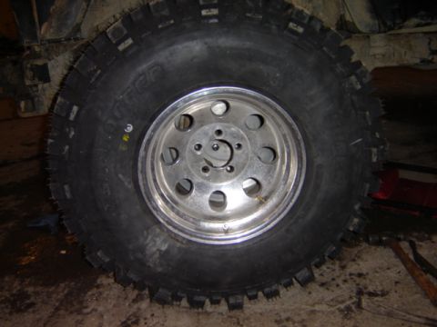 1992 Ford Bronco - Close-up of a vehicle tire and wheel assembly, showing off-road tread pattern and a polished rim.