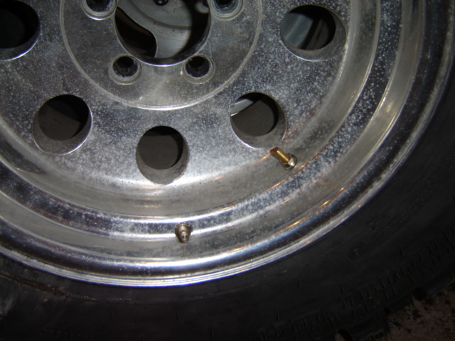 Chrome wheel with two valve stems and visible tire tread