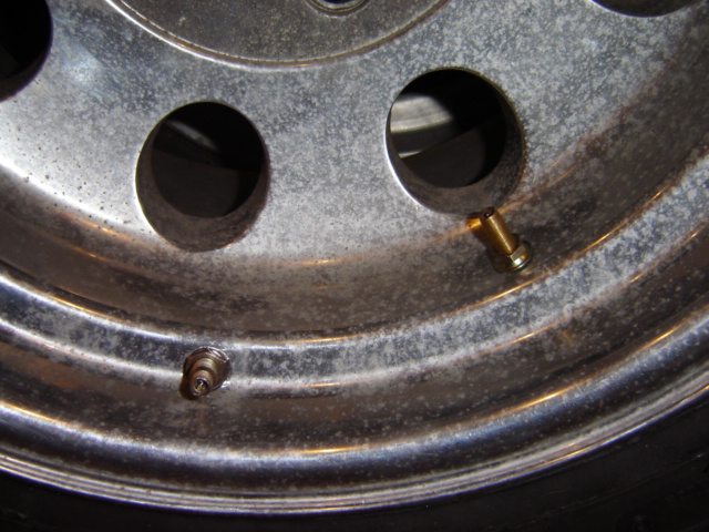 Close-up of a chrome wheel showing two valve stems and some corrosion