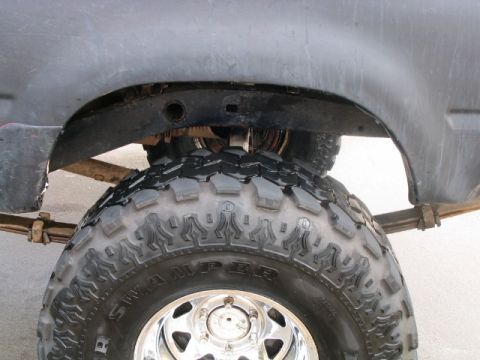 1986 Ford F-150 - Close-up of a truck's rear suspension and tire, showing leaf springs and a large off-road tire.