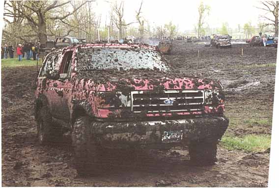 Mud-covered red SUV, front view, with grille details visible
